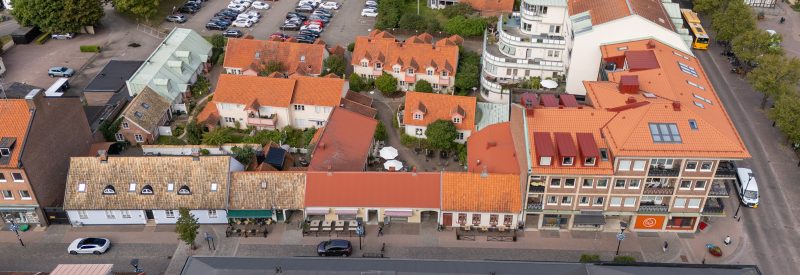 Flygvy över kv. Vakteln sett österifrån. Storgatan 19 utgörs av de mittersta husen, i 1 1/2 plan. Gatuhusen mot Storgatan är av äldre karaktär med putsfasad och bruna tegelpannor. Bostadshusen på innergården är vitputsade med bruna takpannor och omgärdas av grönska. På bilden syns också grannfastigheter av varierande arkitektur.