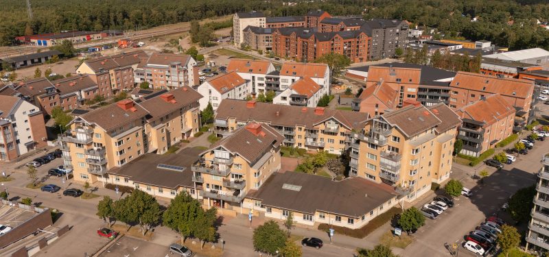 Flygvy över Sockerbruksgatan 8 från sydost. Visar ett hus som varierar mellan en och sju våningar. Fasad klädd i gult tegel, bruna takpannor. Huskropparna omgärdar innergård med uteplats, träd, gräsyta och plattlagda gångar.