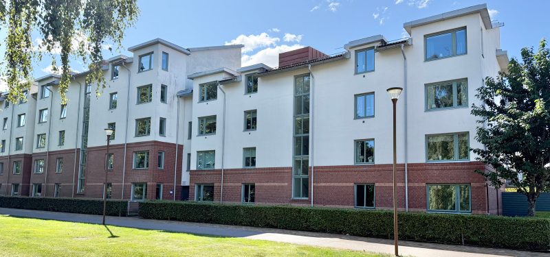 Nybrovägen 3 A-C mot cykelvägen längs Nybrovägen och grönyta med träd. Fastighet i 4 respektive 5 våningar, med en bröstning av brunt tegel och övrig fasad vitputsad. Ljust gröna fönster.