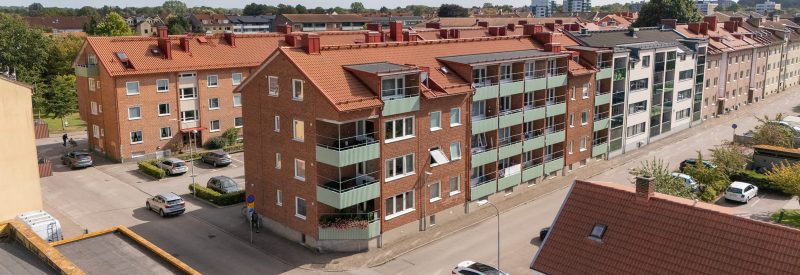 Flygvy som visar Fasangatan 10 och dess fasad mot Fasangatan. Brun tegelfasad, bruna tegelpannor på tak och gröna sinusprofilerade balkongfronter.