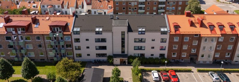 Fasangatan 8, fasad mot innergård och parkering. Vit tegelbyggnad i fyra våningar, mellanliggande mellan två fastigheter i brunt tegel. I förgrunden stor gräsyta samt parkering.