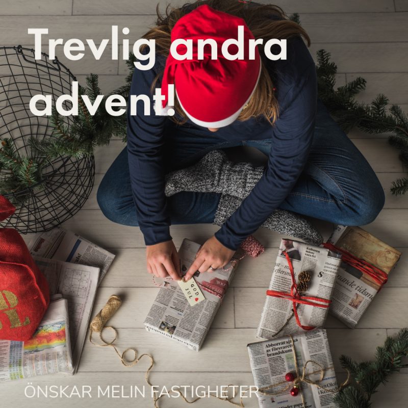 Bild tagen uppifrån på person med tomteluva som sitter i skräddare på golvet och slår in julklappar.